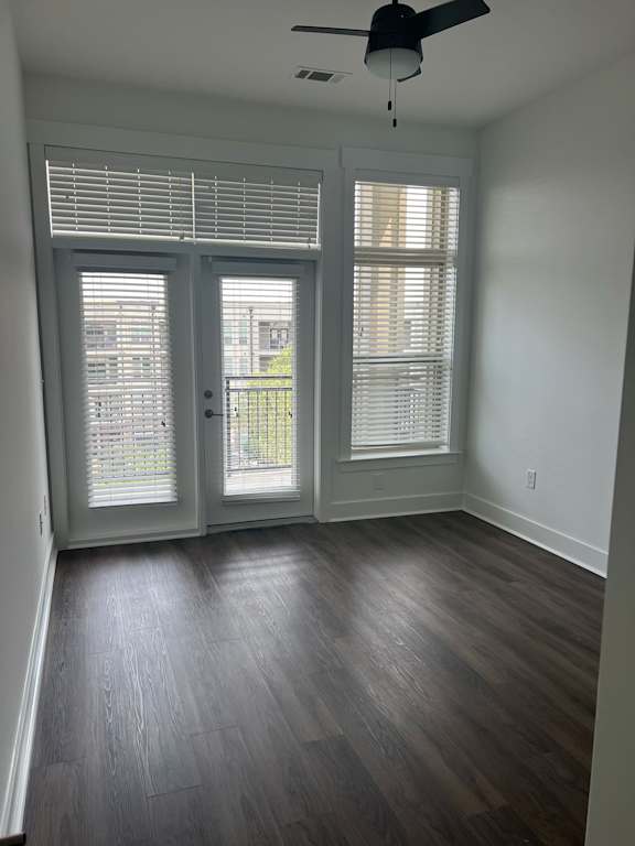 A room with a ceiling fan and sliding glass doors.
