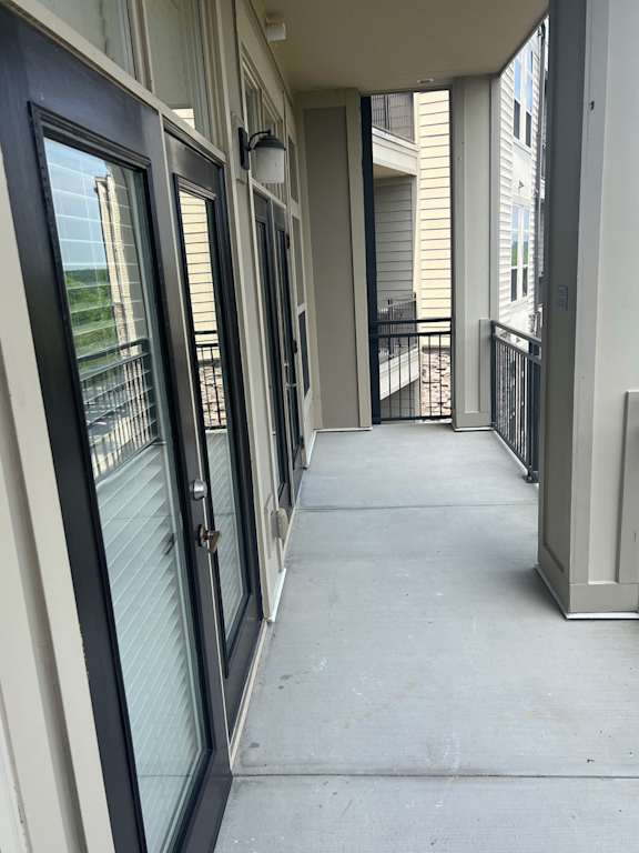 A long hallway with a black railing and white walls.