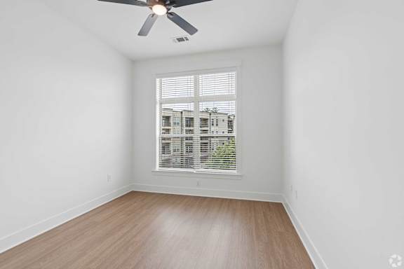 A room with a ceiling fan and a window with blinds.