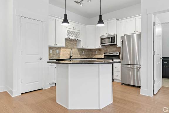 A kitchen with white cabinets and a black countertop.