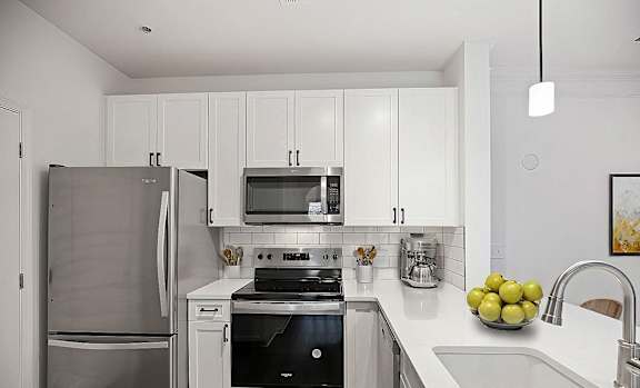 A modern kitchen with a stainless steel refrigerator and a black stove top oven.