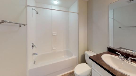 A white toilet sits next to a white bathtub in a bathroom.