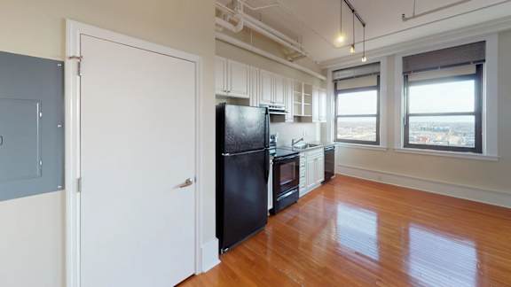 A kitchen with a black fridge and wooden floors.