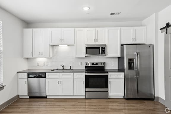 A modern kitchen with white cabinets and stainless steel appliances.