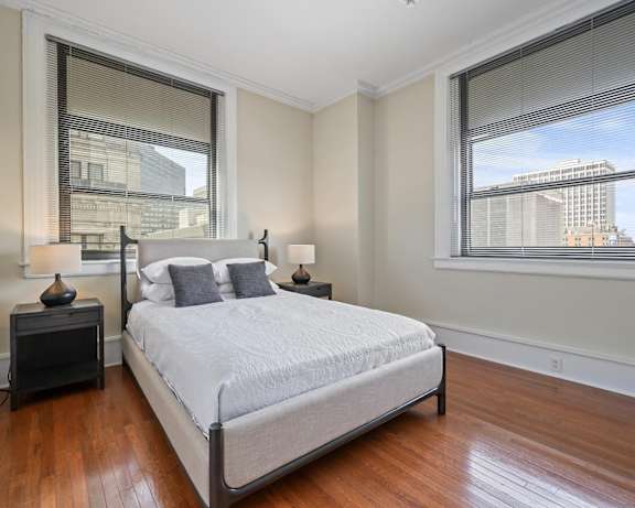 A bedroom with a large bed and a window overlooking a cityscape.