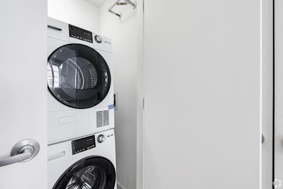 A white front load washing machine with a black door and control panel.