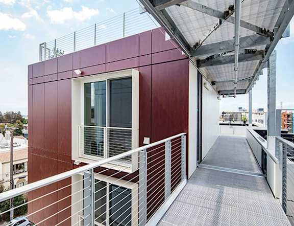 A red building with a white railing and a metal roof.