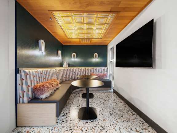 A modern room with a bench, a table and a wall with a painting.