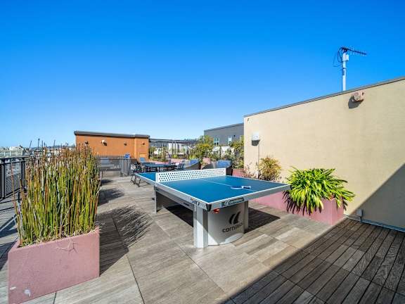A blue table tennis table is on a wooden deck.