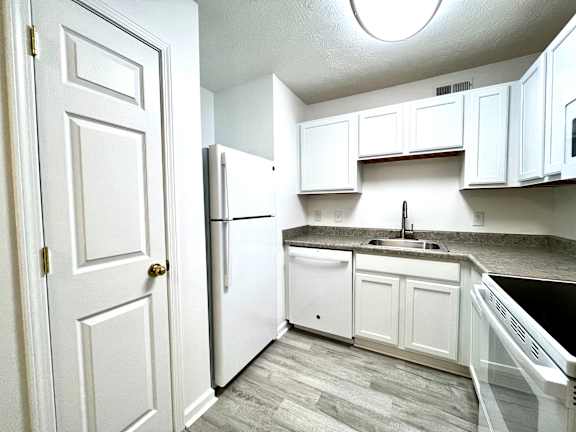A kitchen with white cabinets and a black countertop.