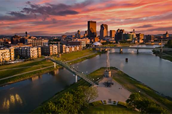 A city skyline is reflected in the water of a river.