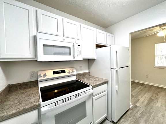 A kitchen with white cabinets and appliances.