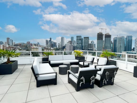a view of the city from a rooftop patio with couches and tables  at Oslo, Seattle, 98102