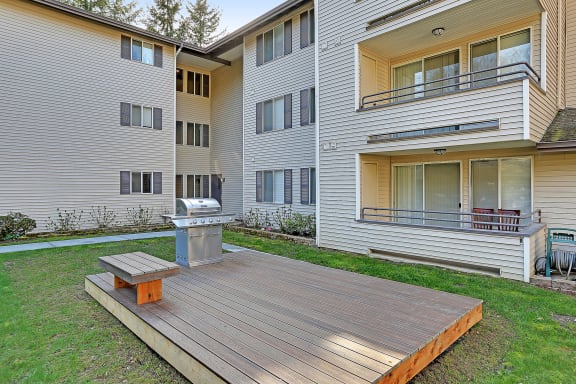 the backyard of an apartment building with a wooden deck and a fire pit  at Townside Flats, Washington