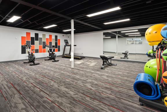 a gym with exercise equipment and a colorful wall in the background