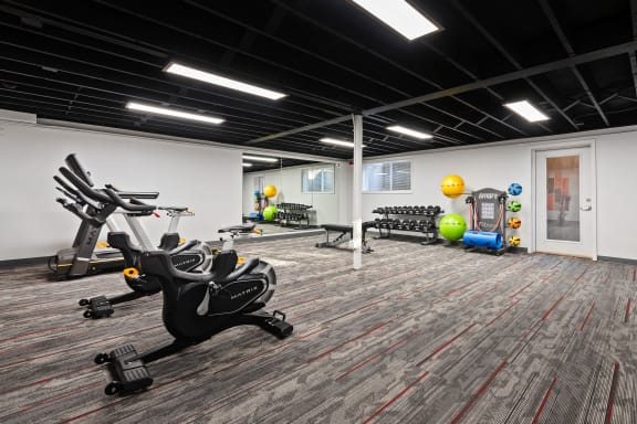 a gym with exercise equipment and weights in a building with white walls and wood floors