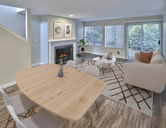 Spacious living area with access to upstairs on the left and private patio access on back wall. Staged with dining set, couch, table and a rug.at Edmonds Gateway, Bremerton