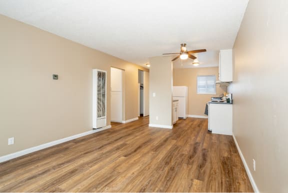 an empty living room with a ceiling fan and a kitchen at Ella 1711 Apartments, California, 95695