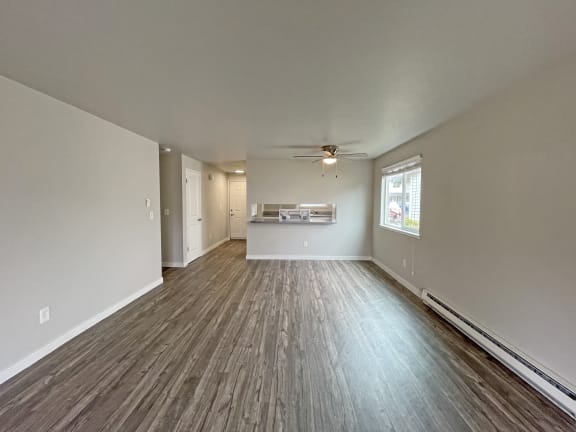 an empty living room with a ceiling fan and a window
