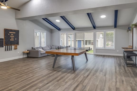 Spacious clubhouse with a ping pong table, games, and a large sectional couch.