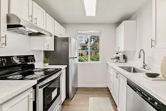 A modern kitchen with white cabinets and stainless steel appliances at The Landing Apartments in Fife, WA.