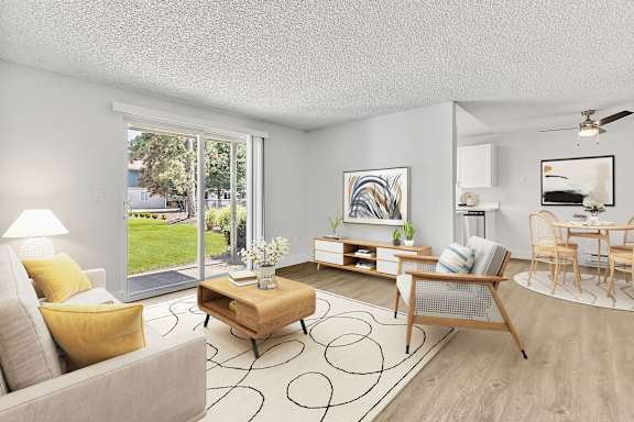 A living room with a grey couch, yellow pillows, a wooden coffee table, and a painting on the wall at The Landing in Fife, WA..