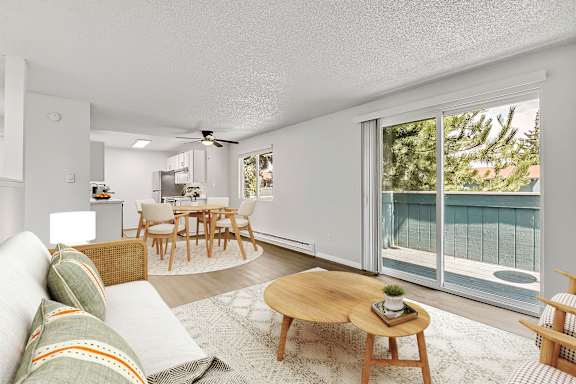 A living room with a couch, a coffee table, and a dining table at The Landing in Fife, WA.