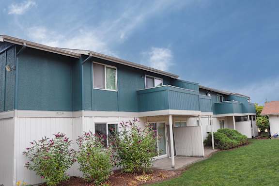 A blue and white building with a green lawn in front.