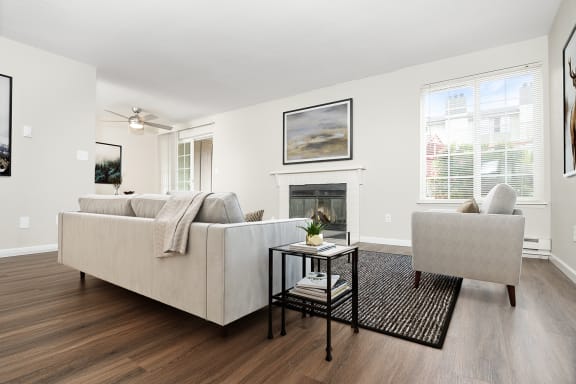 A large and bright living room. Staged with a couch, side tables, a chair and a rug at University Glen, University Place, 98466