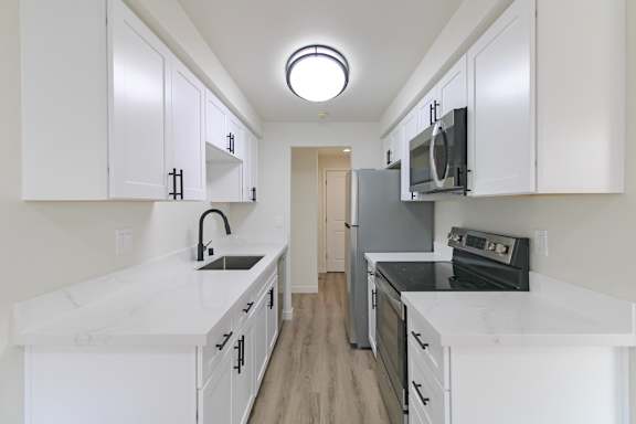 A kitchen with white cabinets and a black stove top oven.