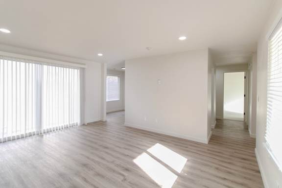 A spacious room with wooden flooring and large windows.