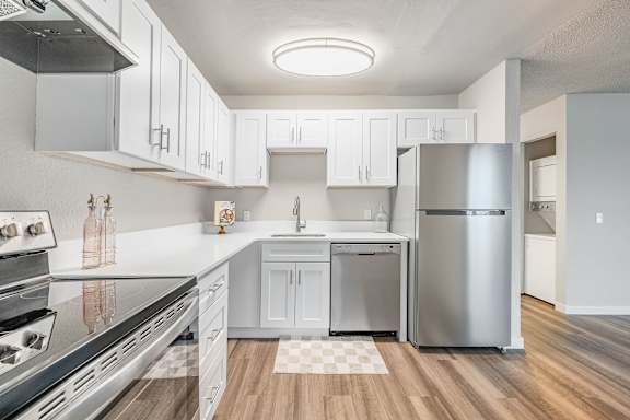 A modern kitchen with white cabinets and stainless steel appliances.