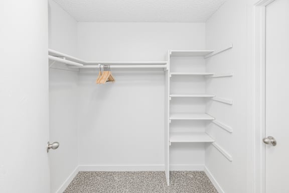 A white closet with a hanger and shelves.