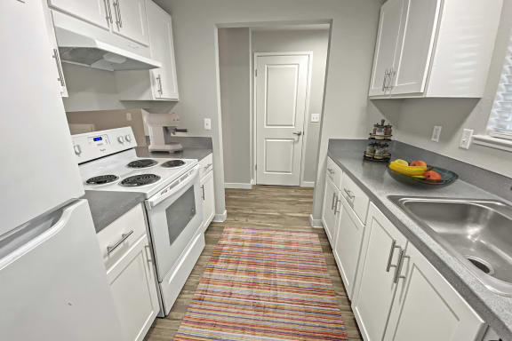 Double galley kitchen, wood-like floors, full-size fridge, top and bottom cabinets, oven, stovetop, and sink.at Quilceda Gardens, Marysville, 98270