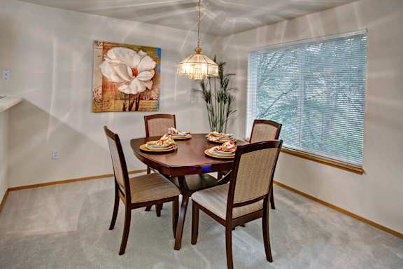 A dining room with a table set for two and a painting on the wall.