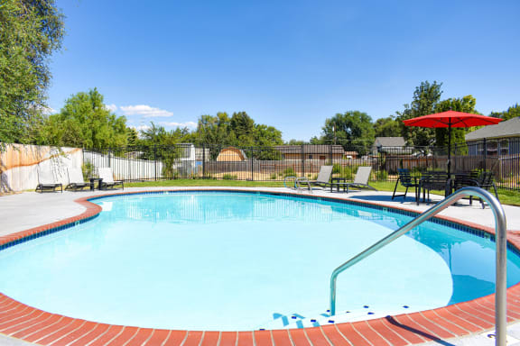 Large blue swimming pool surrounded by grass at Talavera Apartments in Boise, ID.