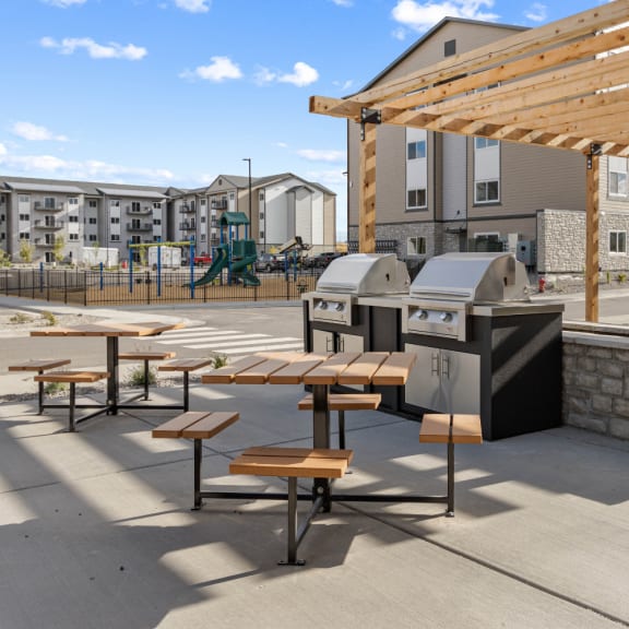 an outdoor patio with picnic tables and barbecue grills in front of a building at Yellowstone Landing, Montana