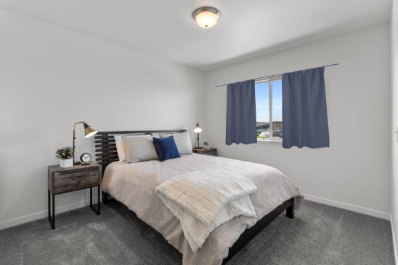 furnished bedroom with white walls and carpeted flooring and a window with blue curtains at Yellowstone Landing, Belgrade, Montana