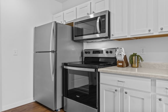 an apartment kitchen with stainless steel appliances and white cabinets at Yellowstone Landing, Montana, 59714