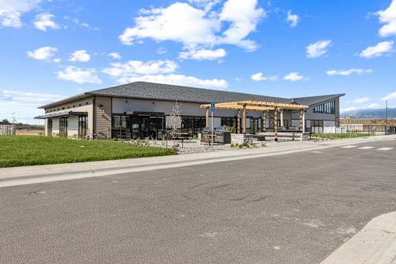 A large building with a grey roof and a covered walkway in front. at Yellowstone Landing, Belgrade, MT, 59714