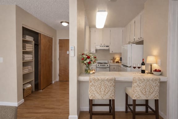 A kitchen with a white counter top and two chairs.
