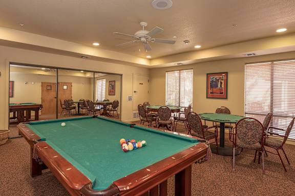 a game room with a pool table and tables  at Winding Commons Senior Living, Carmichael, 95608