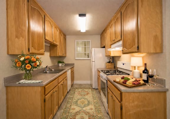 Galley kitchen with wood cabinets and gray countertops at Castle Vista Senior Duplex Community Apartments, California, 95301