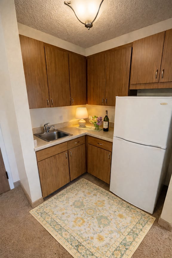 A kitchen with a white fridge and wooden cabinets.