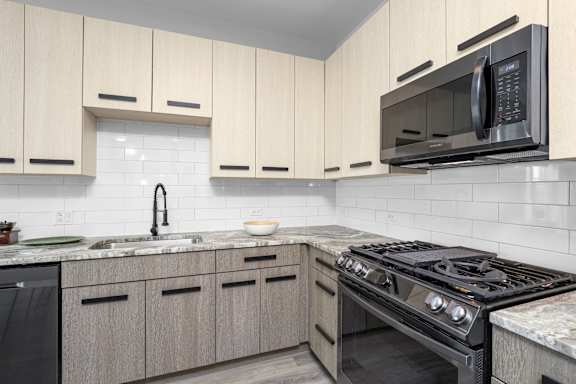 A modern kitchen with a black stove top oven and a black microwave above it.