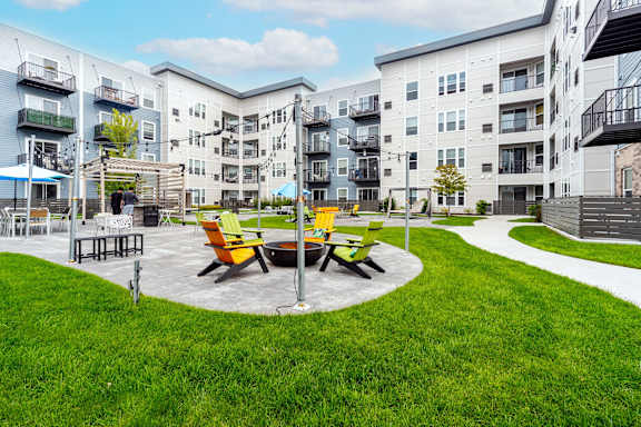 A round table with four chairs is in the middle of a grassy area.