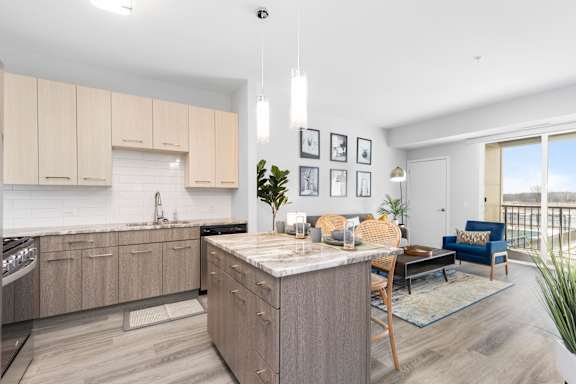 A modern kitchen with wooden cabinets and a marble countertop.