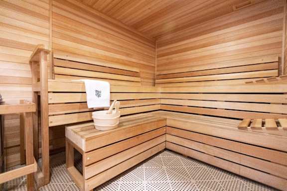 a sauna with a wooden bench and a bucket in it