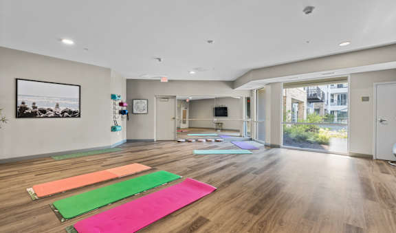 a yoga room with yoga mats on the floor and a large window