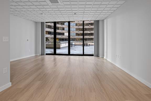 A room with a wooden floor and a large window with a view of a building outside.